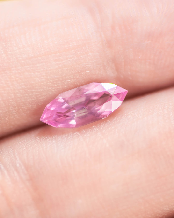 1.50 carat bubblegum pink sapphire displayed on fingertips, revealing radiant sparkle and clarity through the precision marquise mixed cut, untreated sapphire from Sakaraha, Madagascar.
