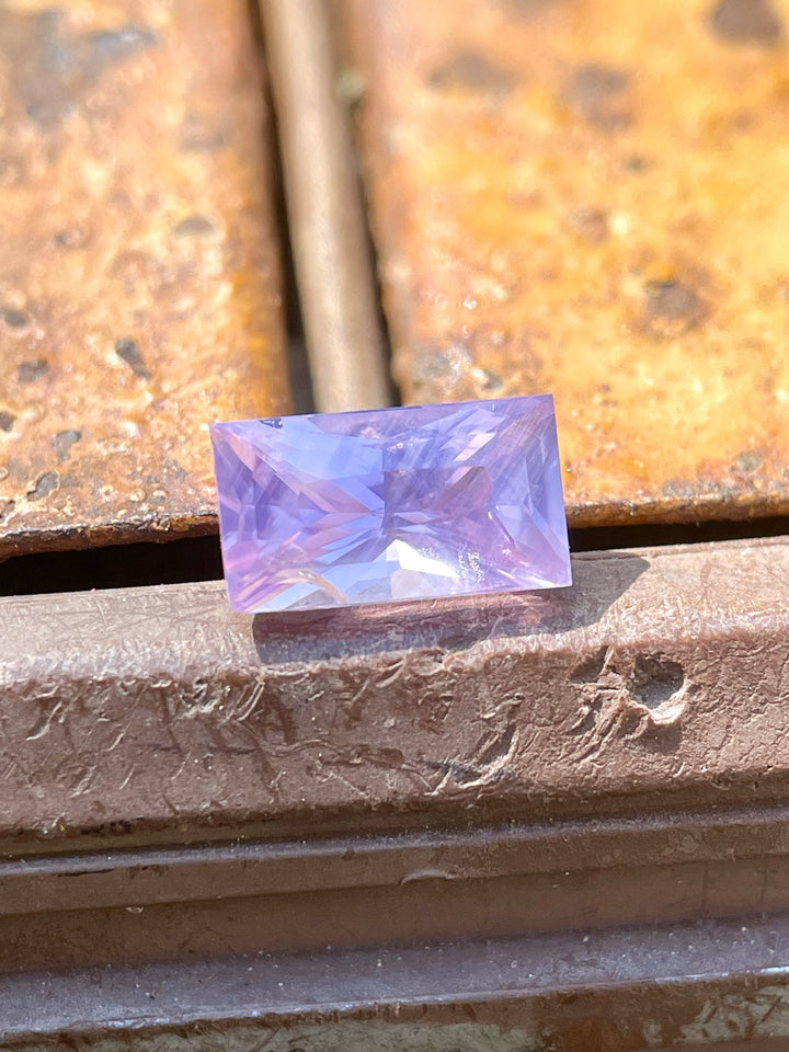 Close-up of a 1.53 carat baguette cut sapphire in opalescent pink and purple hues, ethically sourced from Sri Lanka.