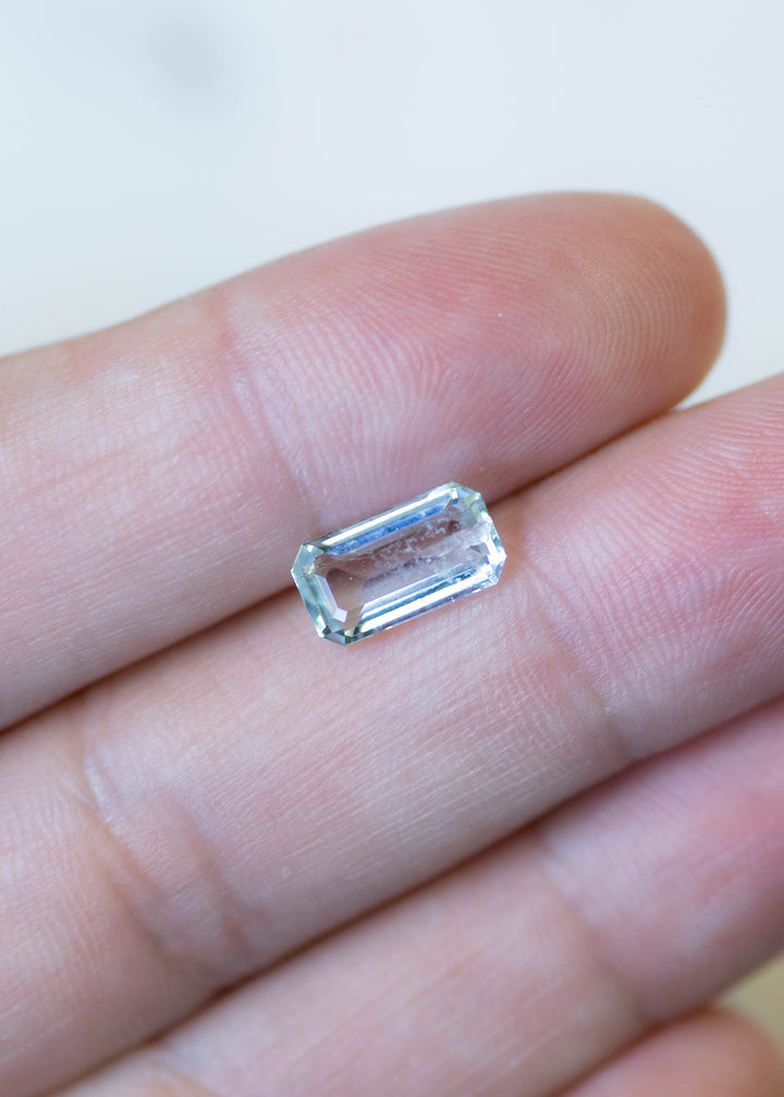 Untreated Colorado aquamarine shown on fingertips for scale, featuring a custom octagonal step cut with elegant elongated proportions.