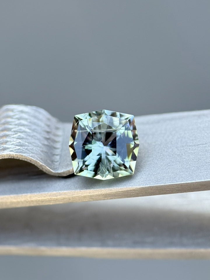 1.55ct custom kite-cut Tanzanite gemstone in mermaid, green, and yellow tones on display showcasing exceptional step-cut brilliance