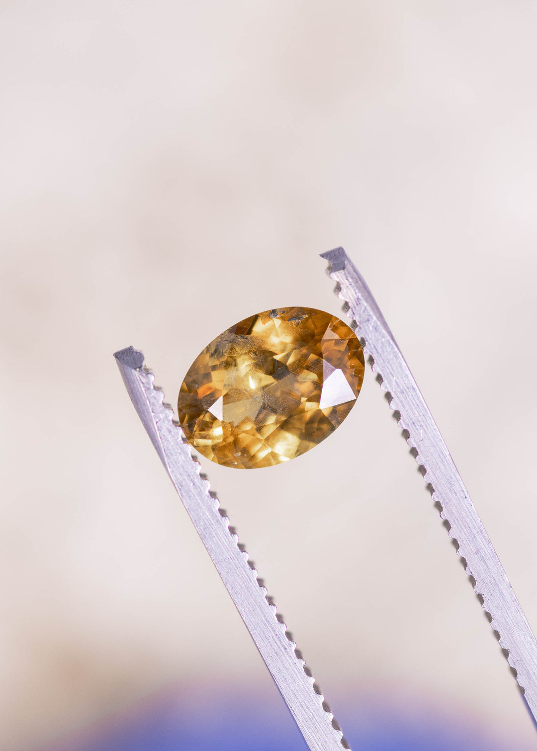 1.56 carat yellow orange Montana sapphire photographed on blue mineral background showing oval mix cut facets and fiery golden orange color from El Dorado Bar Deposit USA
