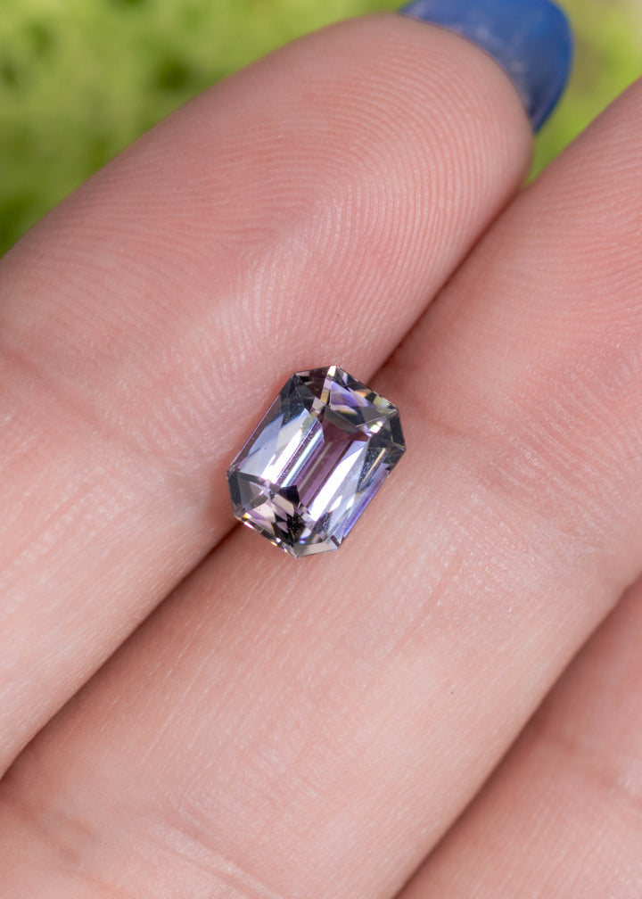 1.56 carat purple champagne teal Tanzanite custom modified radiant resting on finger, Tanzania origin gemstone highlighting brilliant light return, crisp symmetry and modern custom jewelry appeal