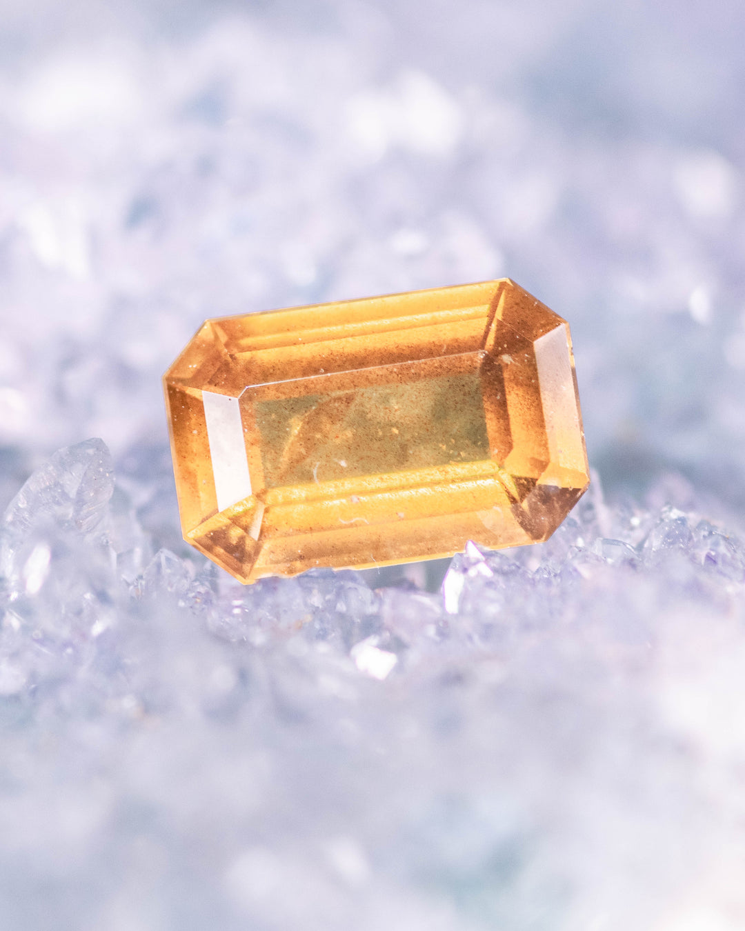 1.57 carat brown and yellow sapphire placed on blue crystal background, showing brilliance and clarity in a modified emerald cut, untreated gemstone from Umba River Valley, Tanga, Tanzania.