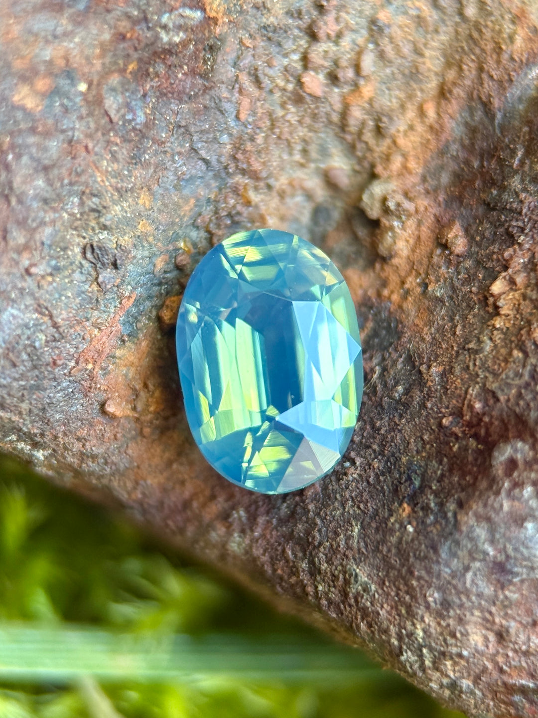 1.57 carat opalescent teal blue green sapphire shown face-up, displaying precision elongated oval faceting and luminous ocean-toned color from Diego, Madagascar.
