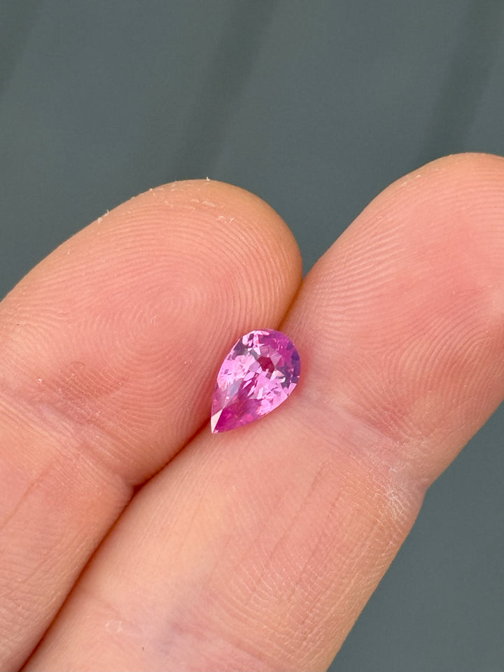 1.57 carat vivid pink kite sapphire from Ratnapura, Sri Lanka, shown on fingertip for scale.