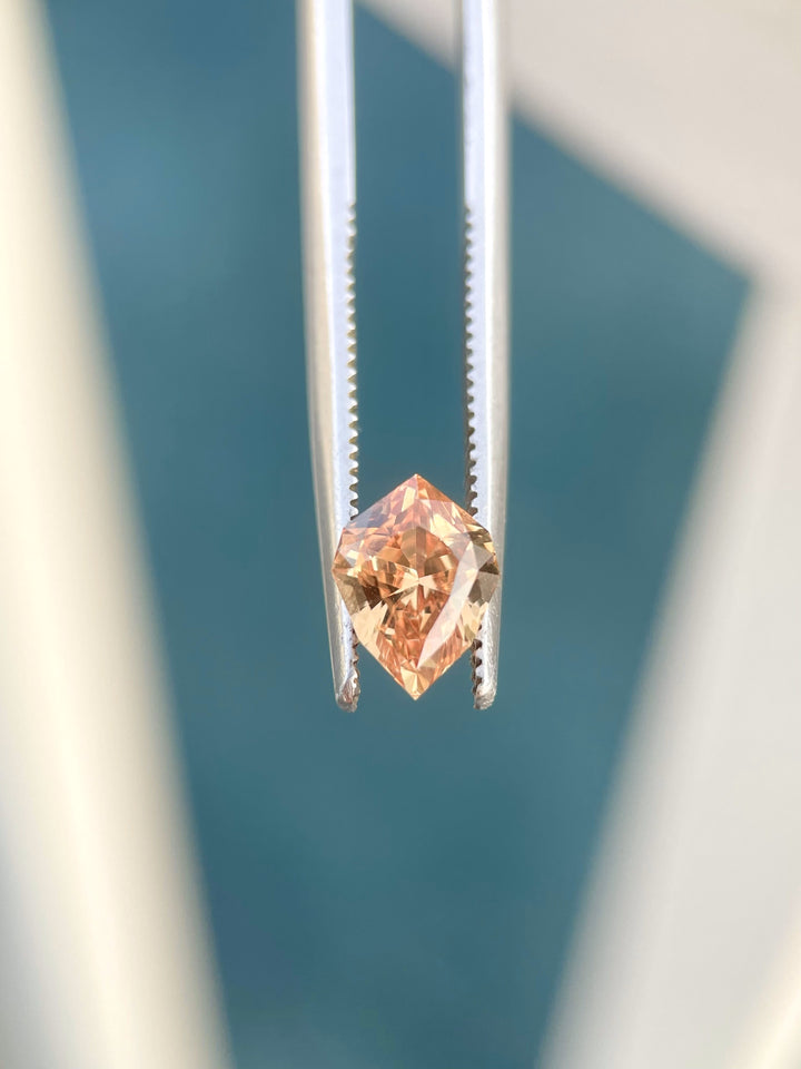 A captivating view of a 1.59-carat sapphire from Sri Lanka, showcasing its warm orange-brown hue and unique geometric shield cut. Natural and untreated, this gemstone radiates a blend of sophistication and modern appeal.