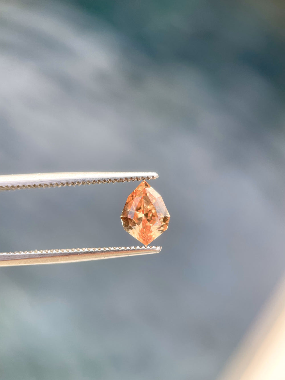 A close-up of the side angle of this 1.59-carat Sri Lankan sapphire, highlighting the precision of its custom geometric shield cut. The gemstone's rich orange and brown tones reflect elegance and warmth.