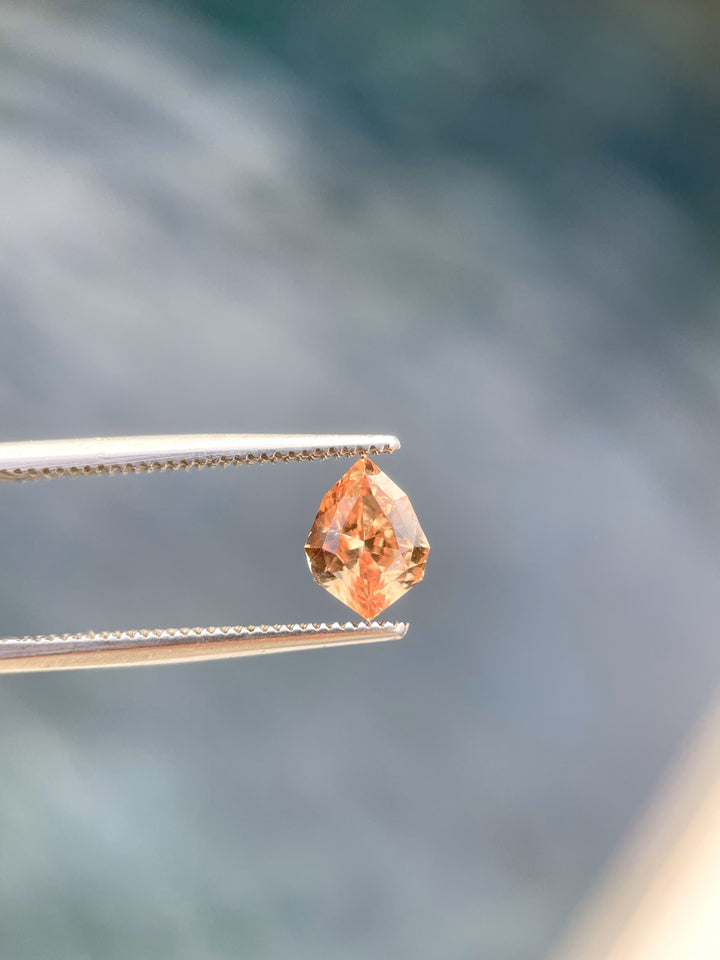 A close-up of the side angle of this 1.59-carat Sri Lankan sapphire, highlighting the precision of its custom geometric shield cut. The gemstone's rich orange and brown tones reflect elegance and warmth.