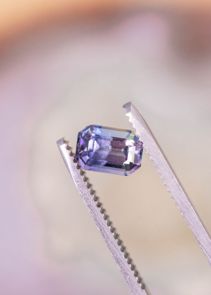 1.60 carat teal green purple Tanzanite emerald cut held in tweezers, untreated Merelani Hills Arusha Tanzania gemstone displaying clean step facets, clarity and trichroic color for fine jewelry design