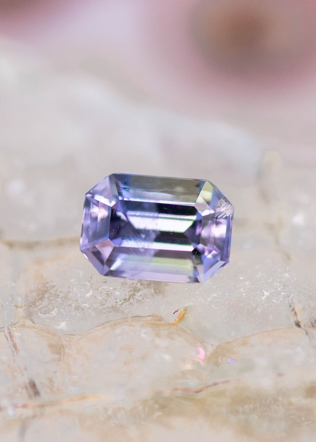 1.60 carat teal green purple Tanzanite emerald cut displayed on natural surface, precision faceted gemstone from Tanzania highlighting geometric symmetry, brilliance and designer appeal for bespoke jewelry