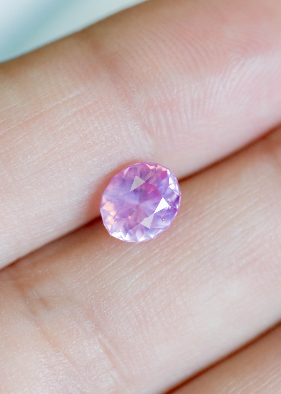 1.61 carat Sri Lankan opalescent vivid pink sapphire oval cut shown on finger for scale