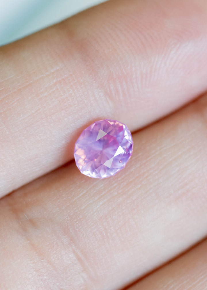 1.61 carat Sri Lankan opalescent vivid pink sapphire oval cut shown on finger for scale