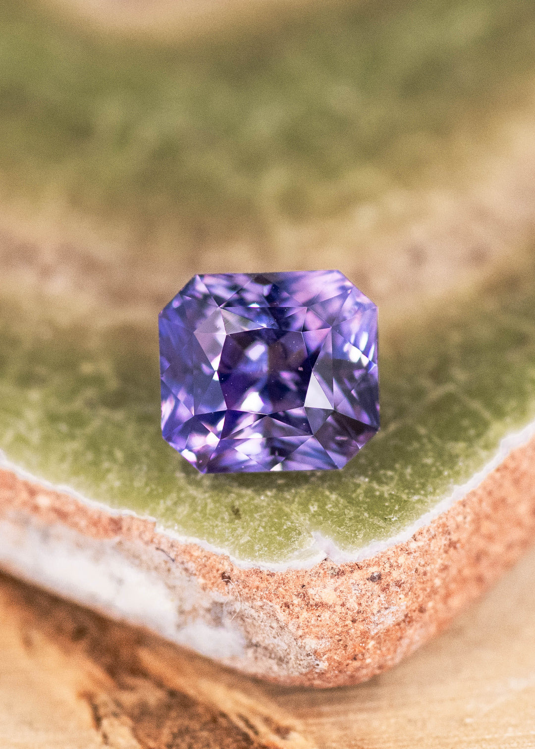 Loose purple and pink sapphire from Sakaraha, Madagascar shown face-up on a display surface, highlighting the precision radiant cut and natural color blend.
