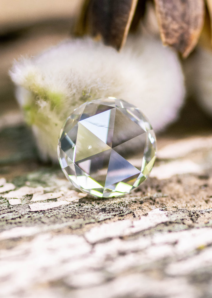 Rose cut light green diamond resting face forward on wooden surface. Displaying clarity and precision faceting.