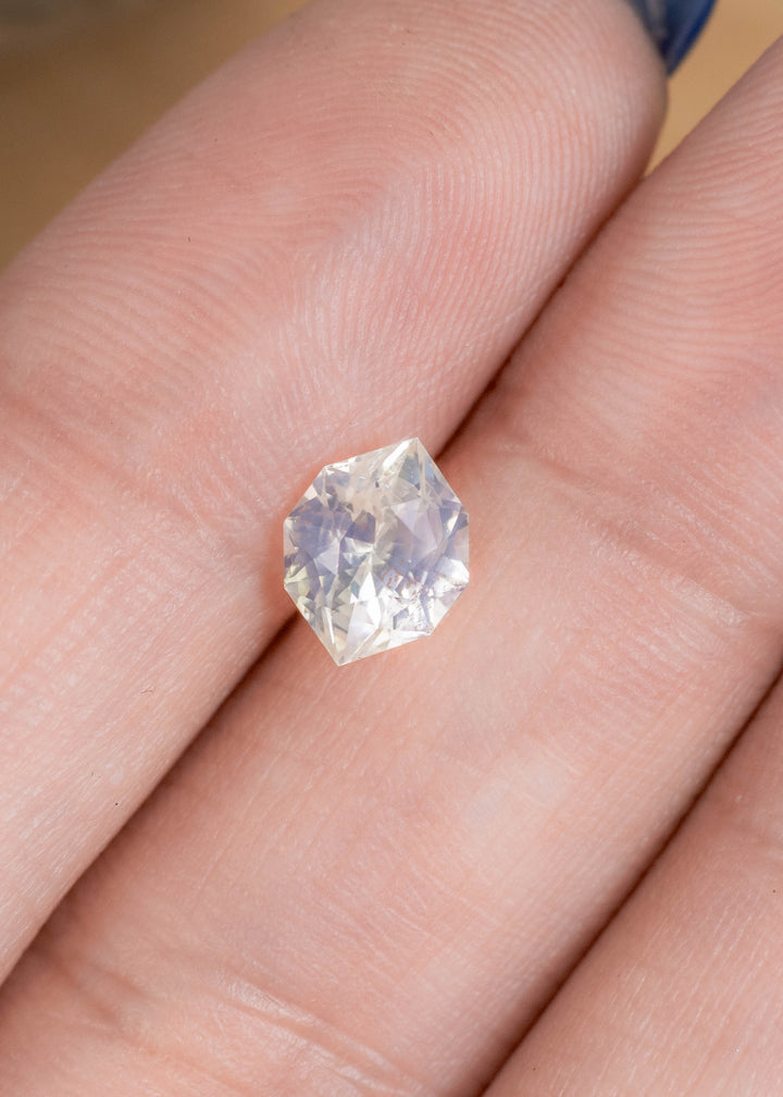 Loose pastel green yellow sapphire from Ratnapura Sri Lanka resting on fingertips displaying the custom geometric marquise cut and natural color shift.