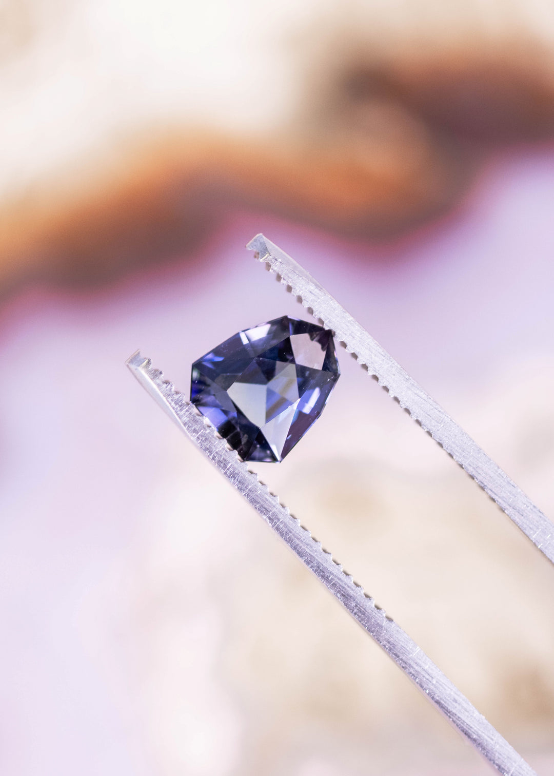 1.66 carat teal green blue purple Tanzanite shield modified brilliant held in tweezers, Merelani Hills Arusha Tanzania gemstone displaying crisp facet reflections, trichroic color and designer cut precision for fine jewelry