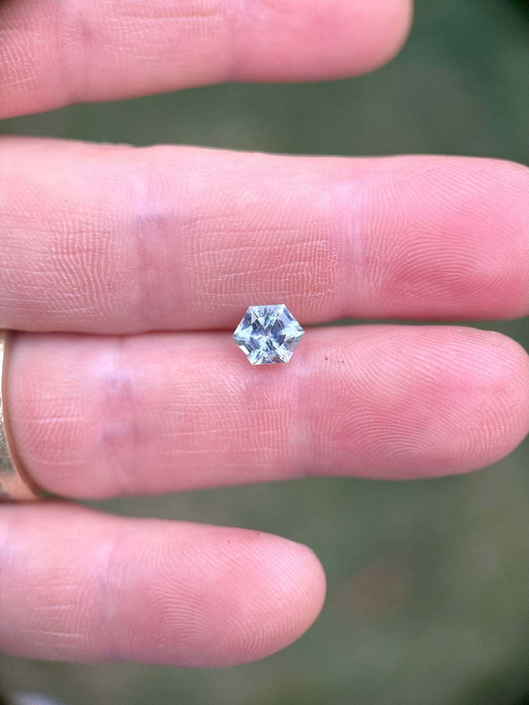 Hand-held Montana sapphire with hexagonal precision cut in teal and powder blue hues