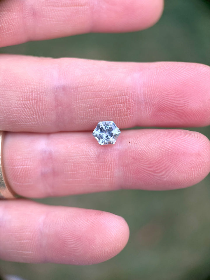 Hand-held Montana sapphire with hexagonal precision cut in teal and powder blue hues