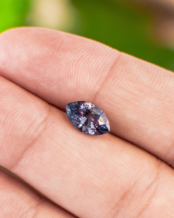 1.68 carat violet-gray sapphire displayed on fingertips, showing its delicate color shift and luster of the precision marquise mixed cut, untreated gemstone from Sakaraha, Madagascar.