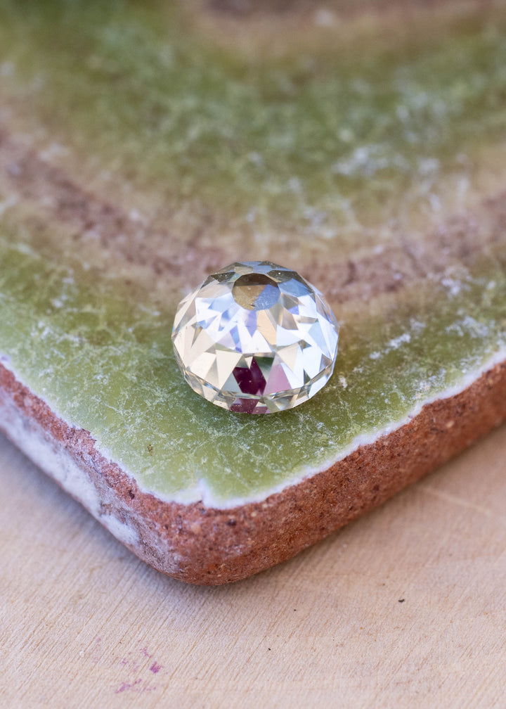1.68 carat round Mughal cut diamond resting on a textured green surface, showing its domed profile and broad antique-style faceting.