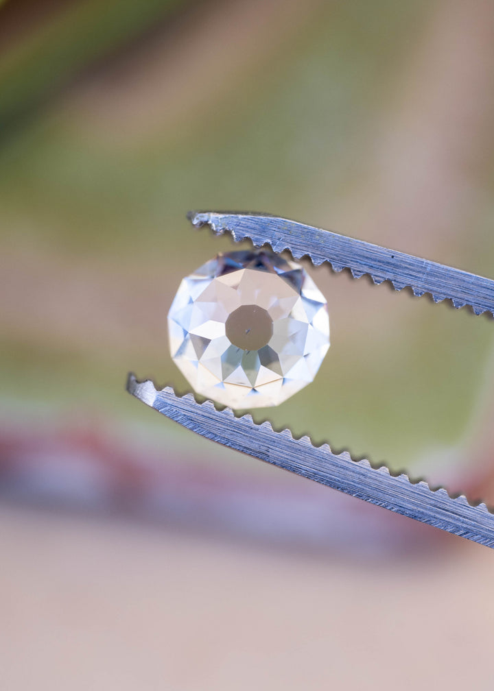 Face-up view of a 1.68 carat Mughal cut diamond held in jeweler’s tweezers, showing the small central table and radial arrangement of broad facets.