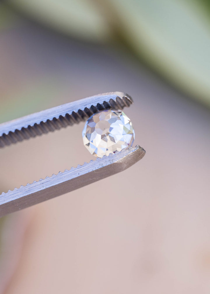 Angled view of the 1.68 carat diamond in tweezers, highlighting its softly rounded outline, deep profile and hand-worked appearance.
