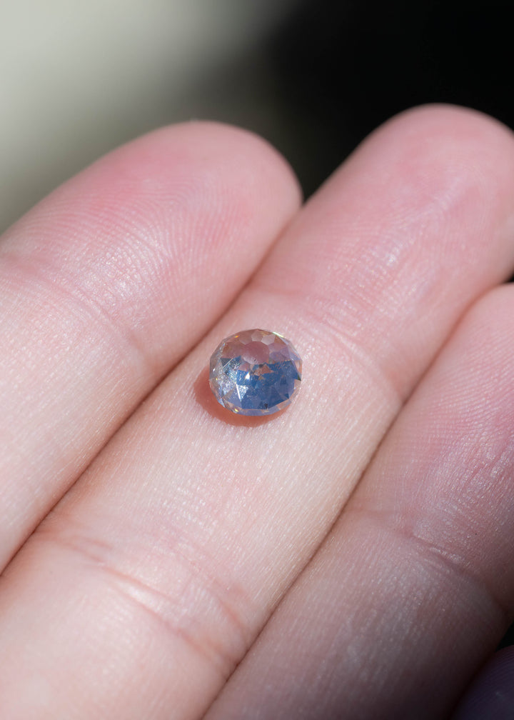 1.68 carat Mughal cut diamond resting on fingertips for scale, with blue and warm reflections visible across its antique-style facets.