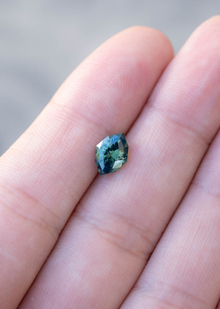 1.68ct green teal geometric marquise sapphire from Diego, Madagascar held on finger tips under natural lighting to show scale and color.