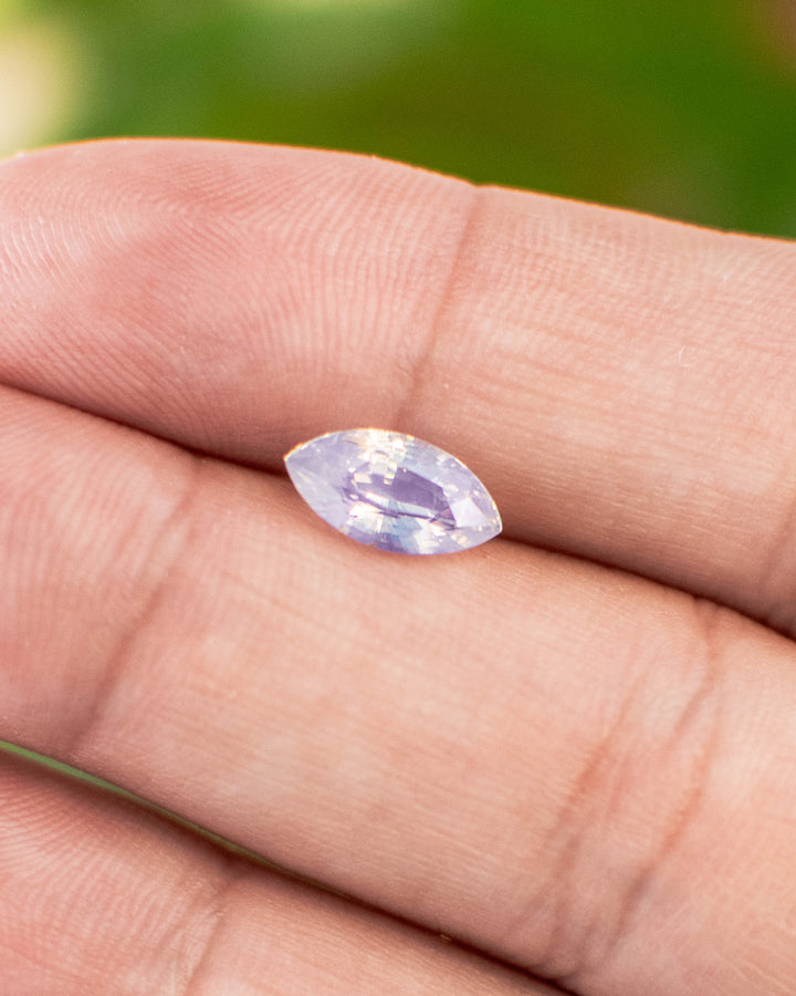 1.70 carat blue opalescent sapphire shown on fingertip, reflecting natural daylight and precision faceting of the marquise mixed cut, untreated gemstone from Ratnapura, Sri Lanka.