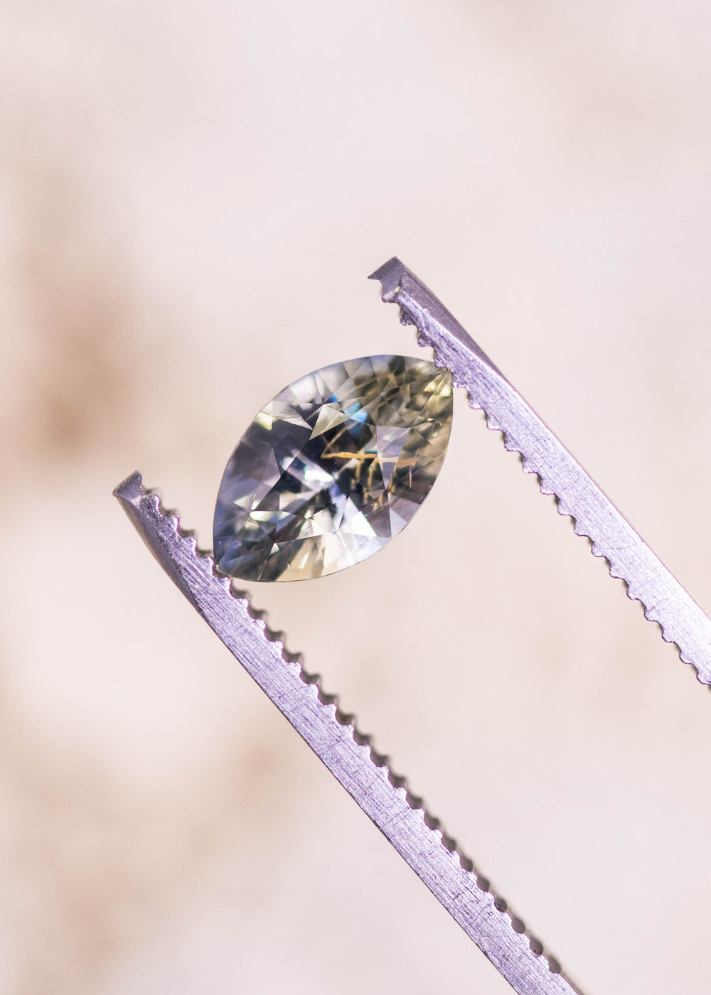 Loose parti yellow, blue, and green sapphire held in jeweler’s tweezers showing the precision marquise mixed cut and natural color zoning from Sakaraha Madagascar.