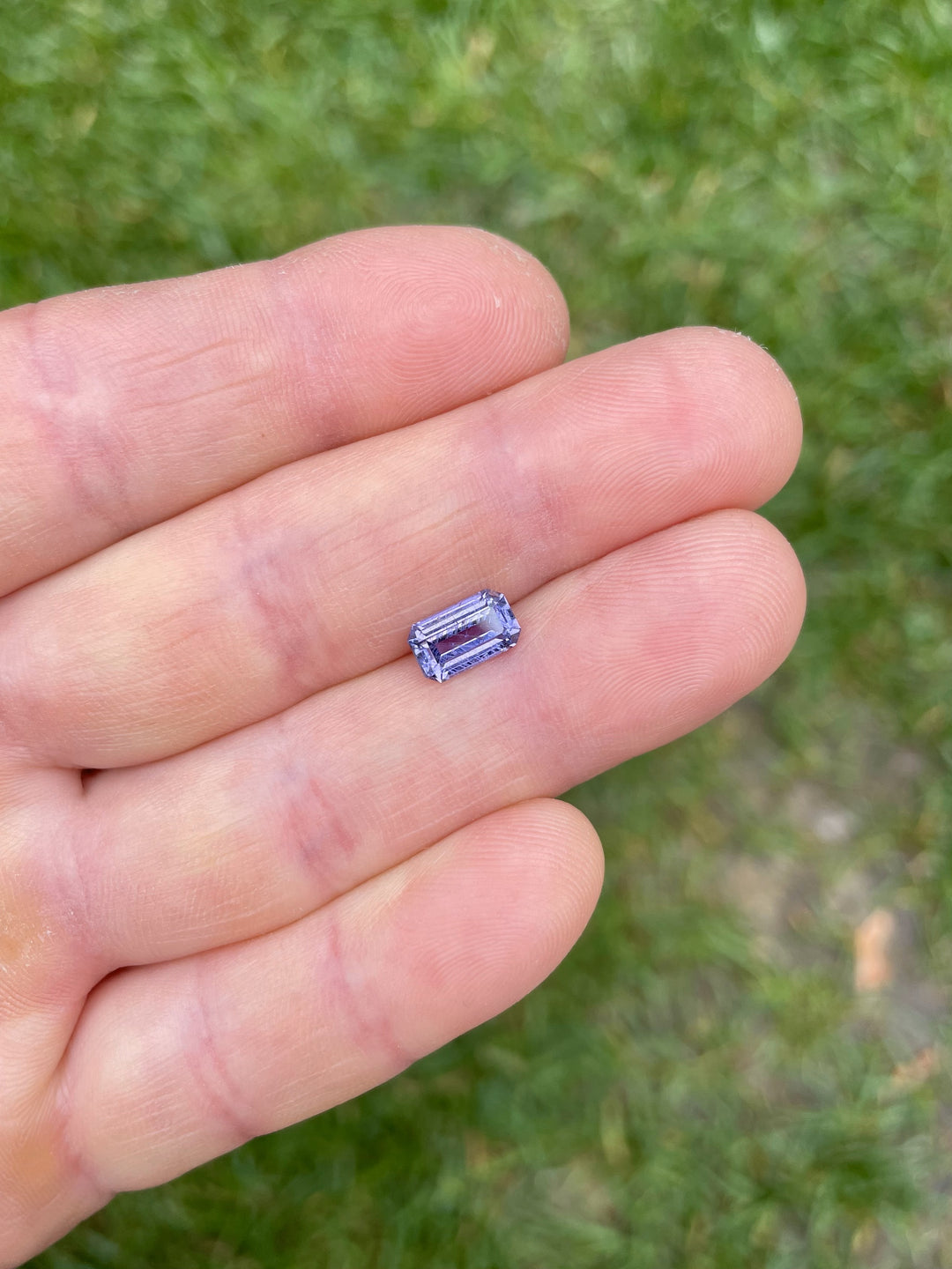 1.74 carat violet sapphire displayed on fingertip, showing scale and antique-style elongated emerald cut from Umba River, Tanzania