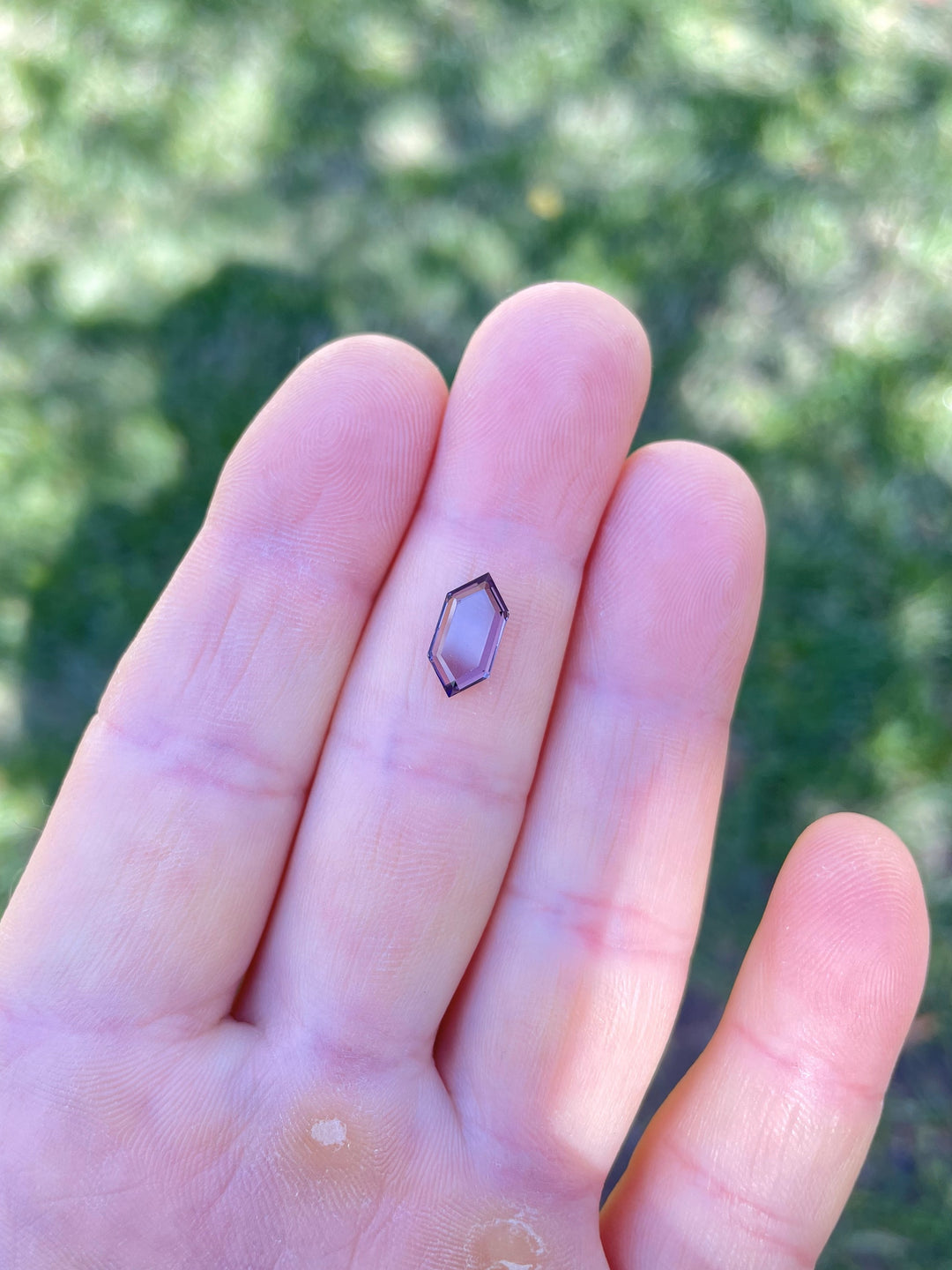 Hand holding a 1.77-carat hexagonal step cut Purple - Pink  spinel, ethically sourced from Sri Lanka.