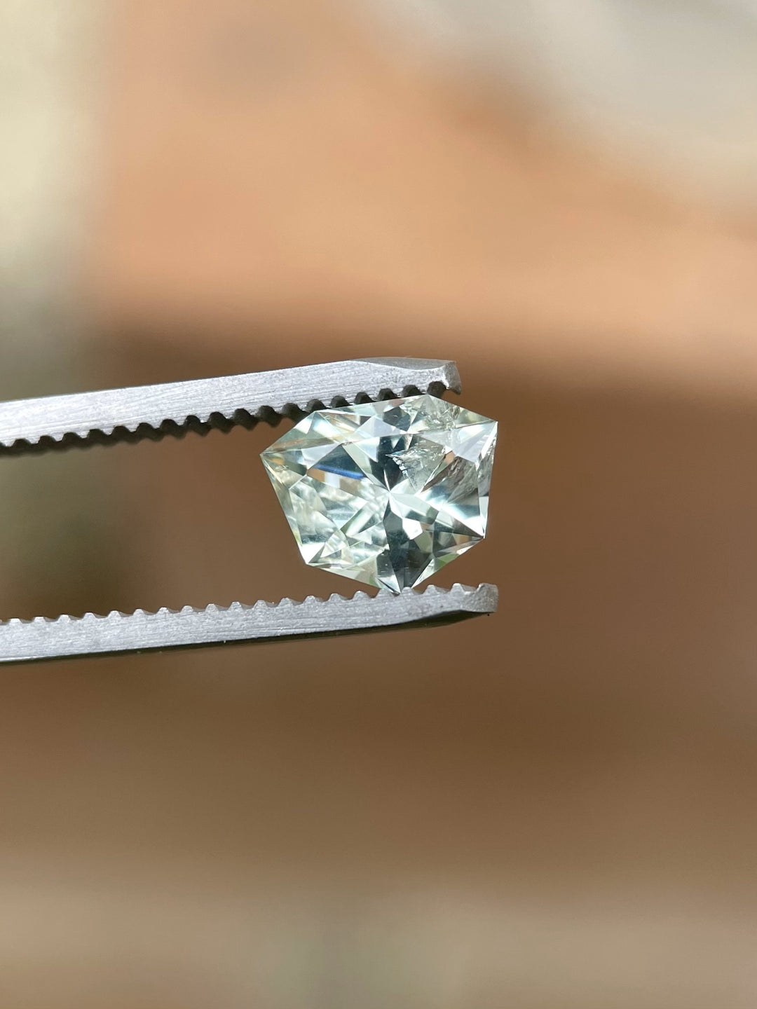 1.80 carat trillion cut sapphire in yellow, green, and blue hues held in tweezers, unheated and sourced from Chimwadzulu Hill, Malawi.