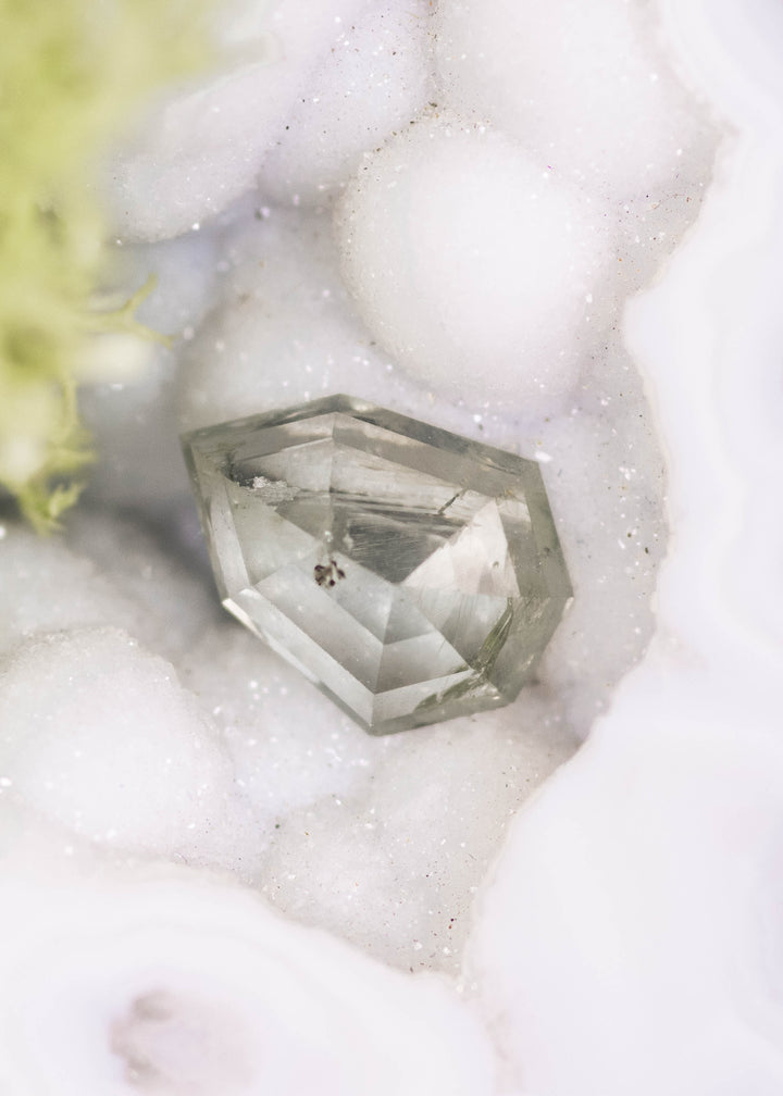 1.82 carat untreated Montana sapphire in teal and seafoam tones displayed on white crystal matrix, custom shield rose cut showing natural brilliance and faceting.