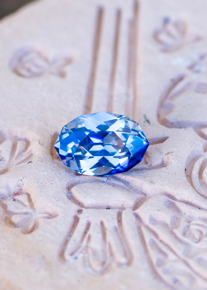 1.85ct blue and white parti sapphire in a custom moval brilliant cut from Sri Lanka resting on carved stone.