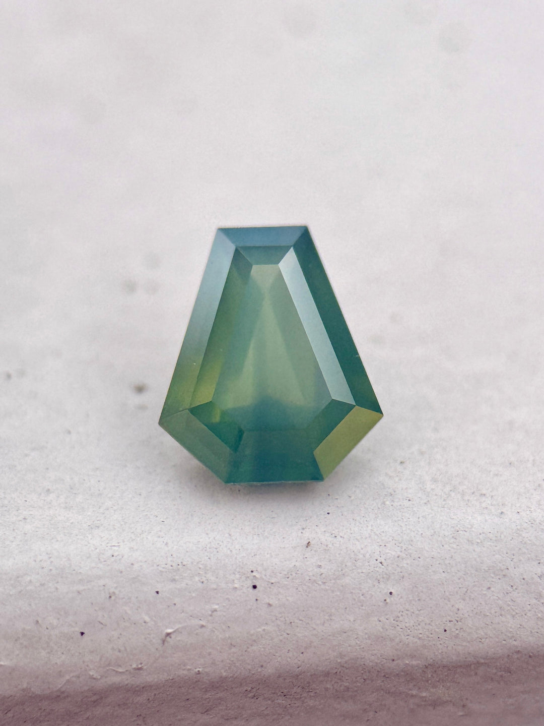 1.88 carat opalescent teal blue green sapphire shown face-up, displaying shield step cut faceting and luminous ocean-toned color from Garba Tula, Kenya.
