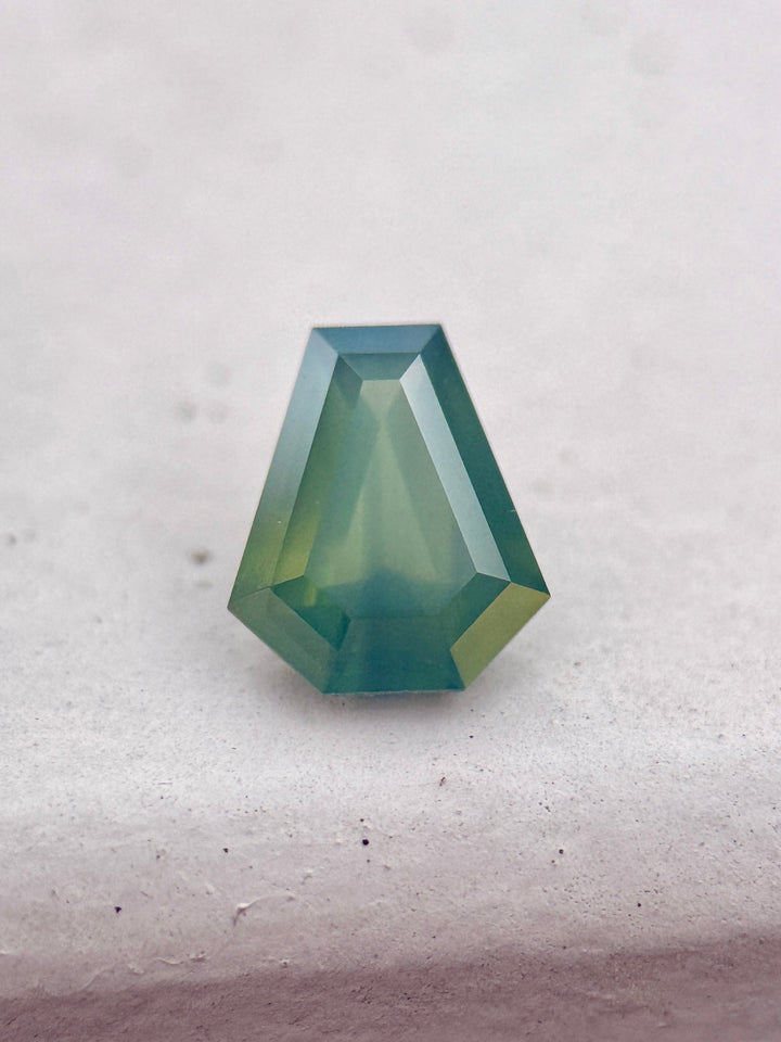 1.88 carat opalescent teal blue green sapphire shown face-up, displaying shield step cut faceting and luminous ocean-toned color from Garba Tula, Kenya.