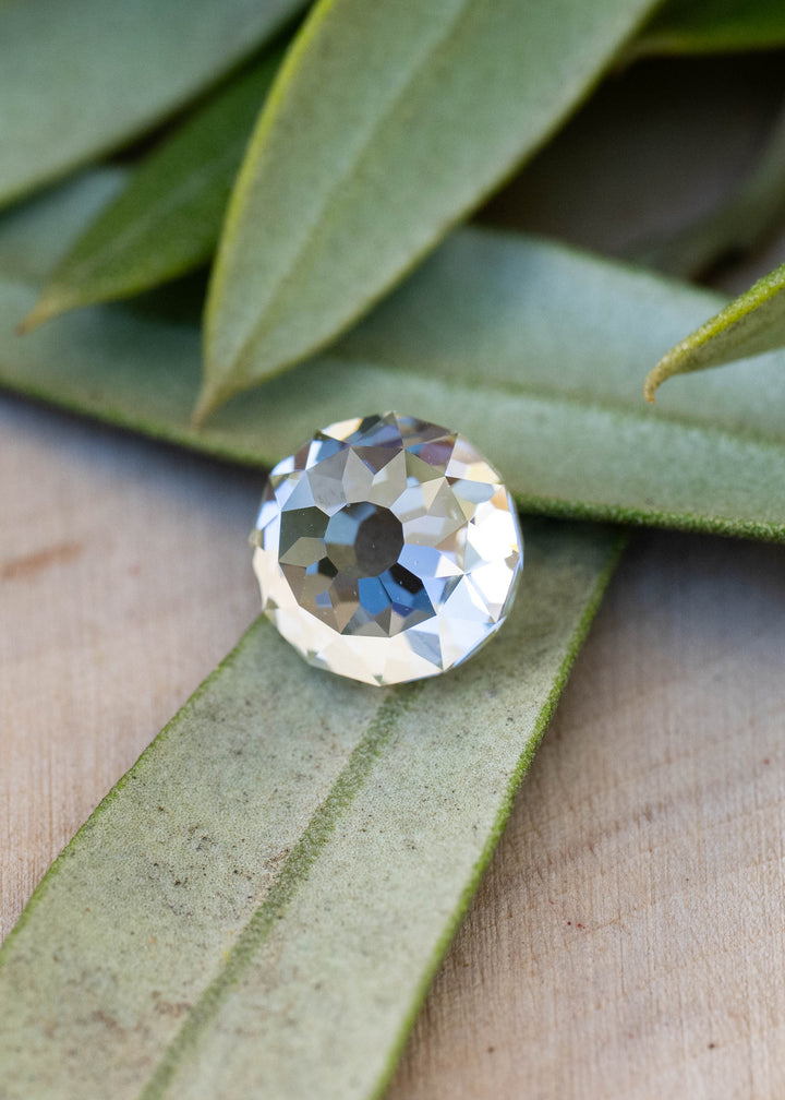 Low-angle view of a 1.92 carat Mughal cut diamond among green leaves, showing its domed profile and broad faceting across the crown.