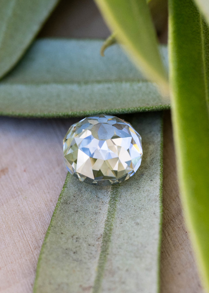 Angled face-up view of the round Mughal cut diamond displaying its open center and mosaic of warm champagne, cool silver and green reflections.