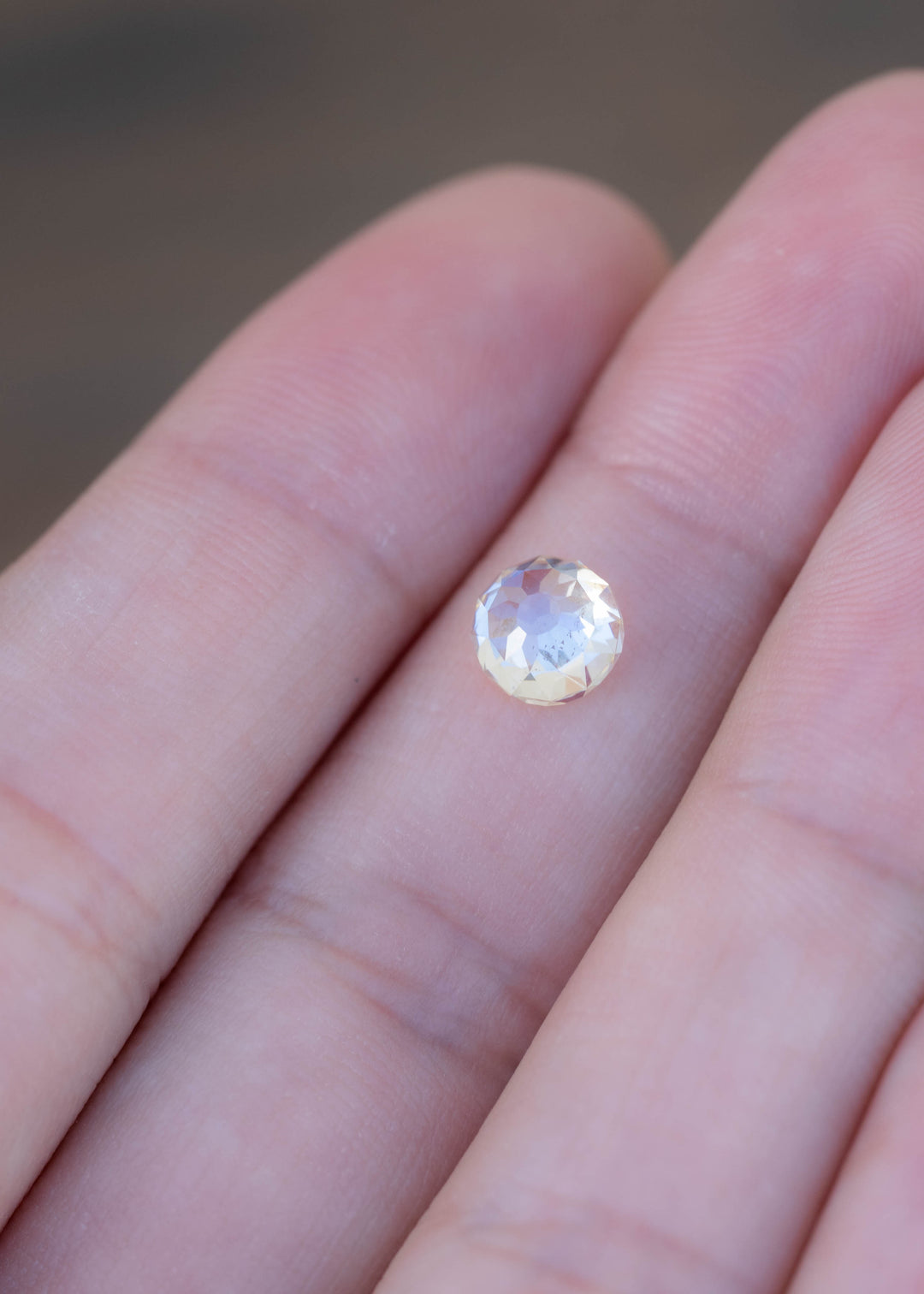 Round 1.92 carat Mughal cut diamond resting on a fingertip for scale, showing its pale warm tone, broad facets and natural inclusions.