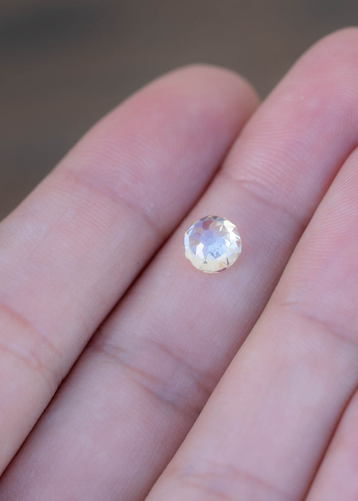 Round 1.92 carat Mughal cut diamond resting on a fingertip for scale, showing its pale warm tone, broad facets and natural inclusions.