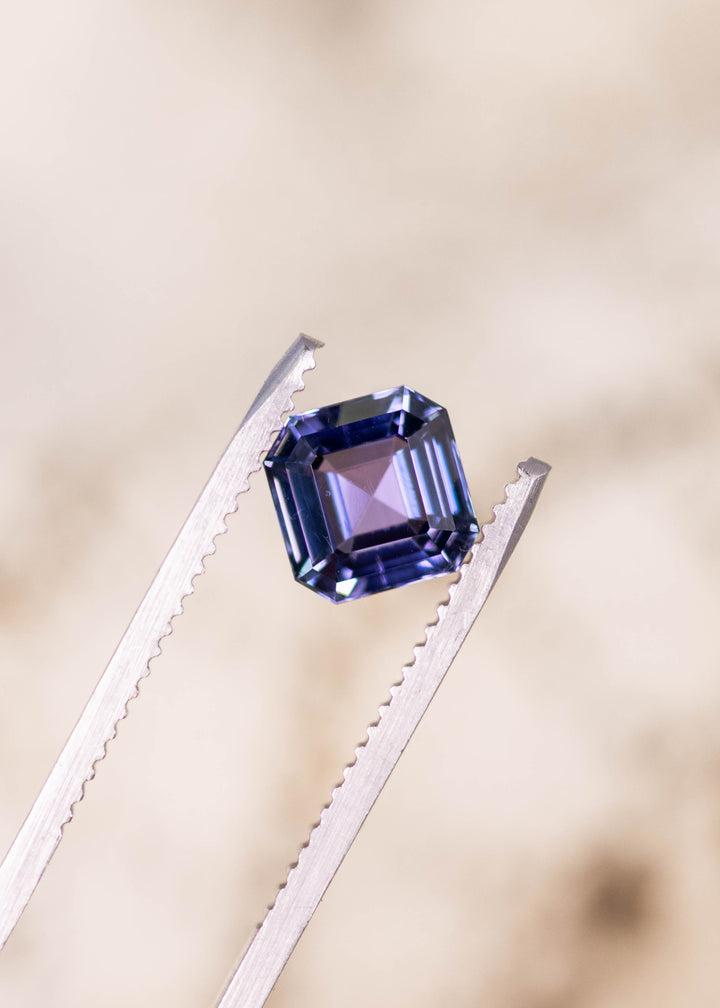 1.93 carat blue violet Tanzanite Asscher cut held in tweezers, square step cut gemstone from Merelani Hills Arusha Tanzania displaying clean concentric facets, brilliance and clarity for fine custom jewelry design