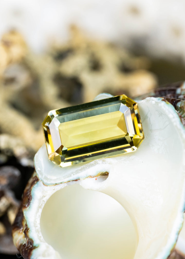 Natural untreated 2.06 carat yellow-green tanzanite with a precision geometric emerald-style cut displayed in natural light.