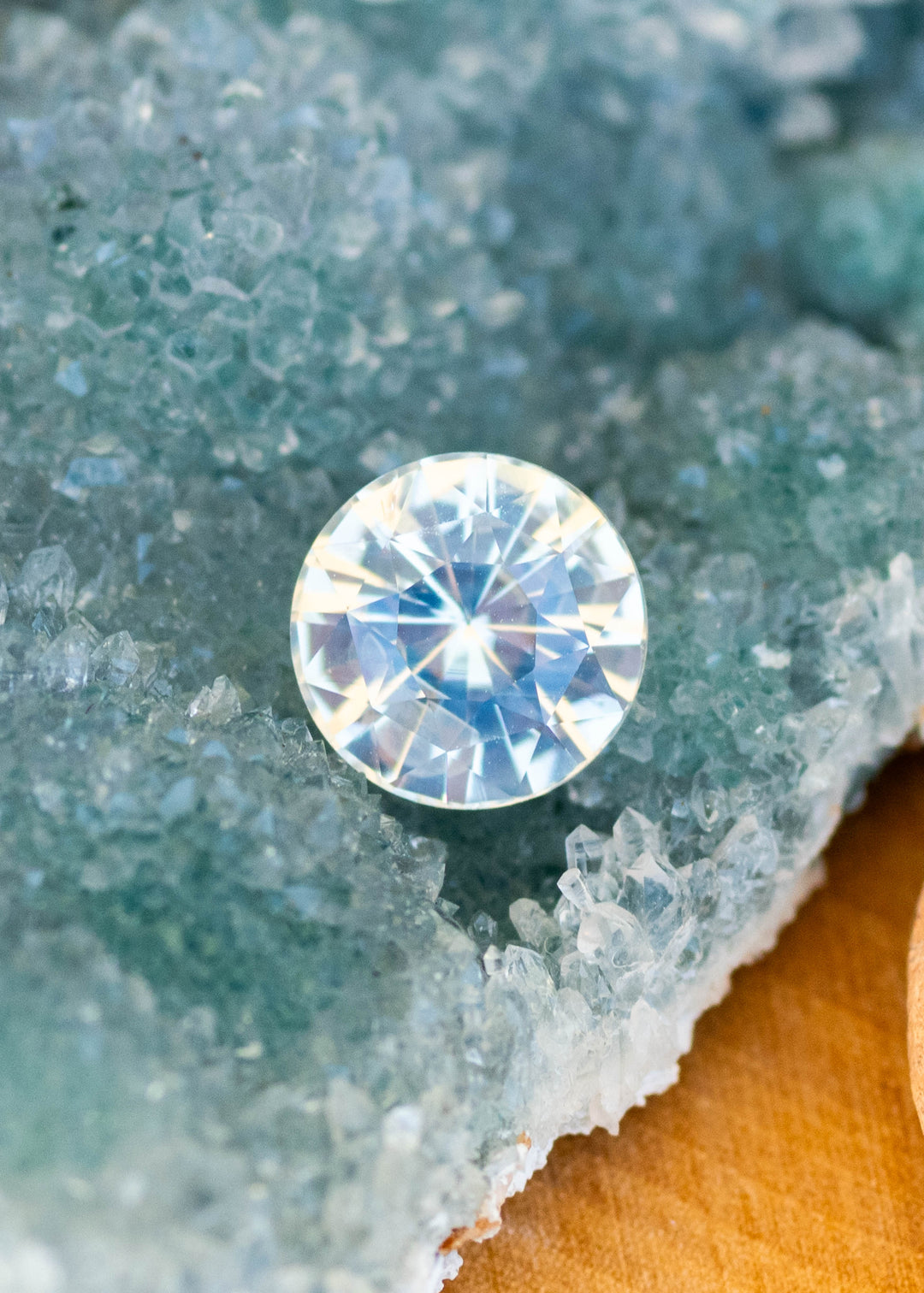 Natural round white opalescent sapphire resting on natural blue amethyst surface.