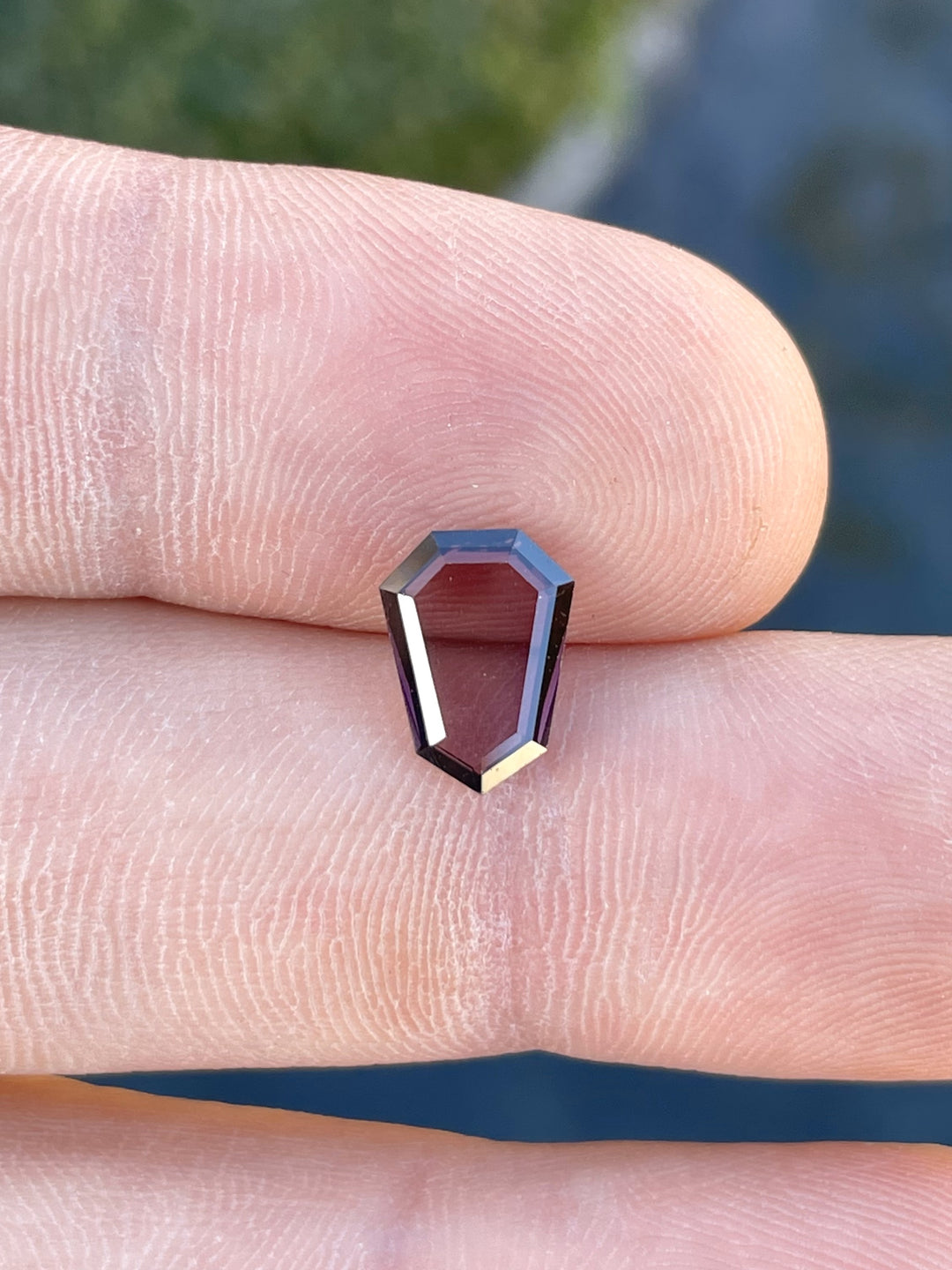Close-up of a 2.05 carat red-purple spinel gemstone with a shield step cut portrait, sourced from Sri Lanka and untreated, showcasing a mix of pink and purple hues.