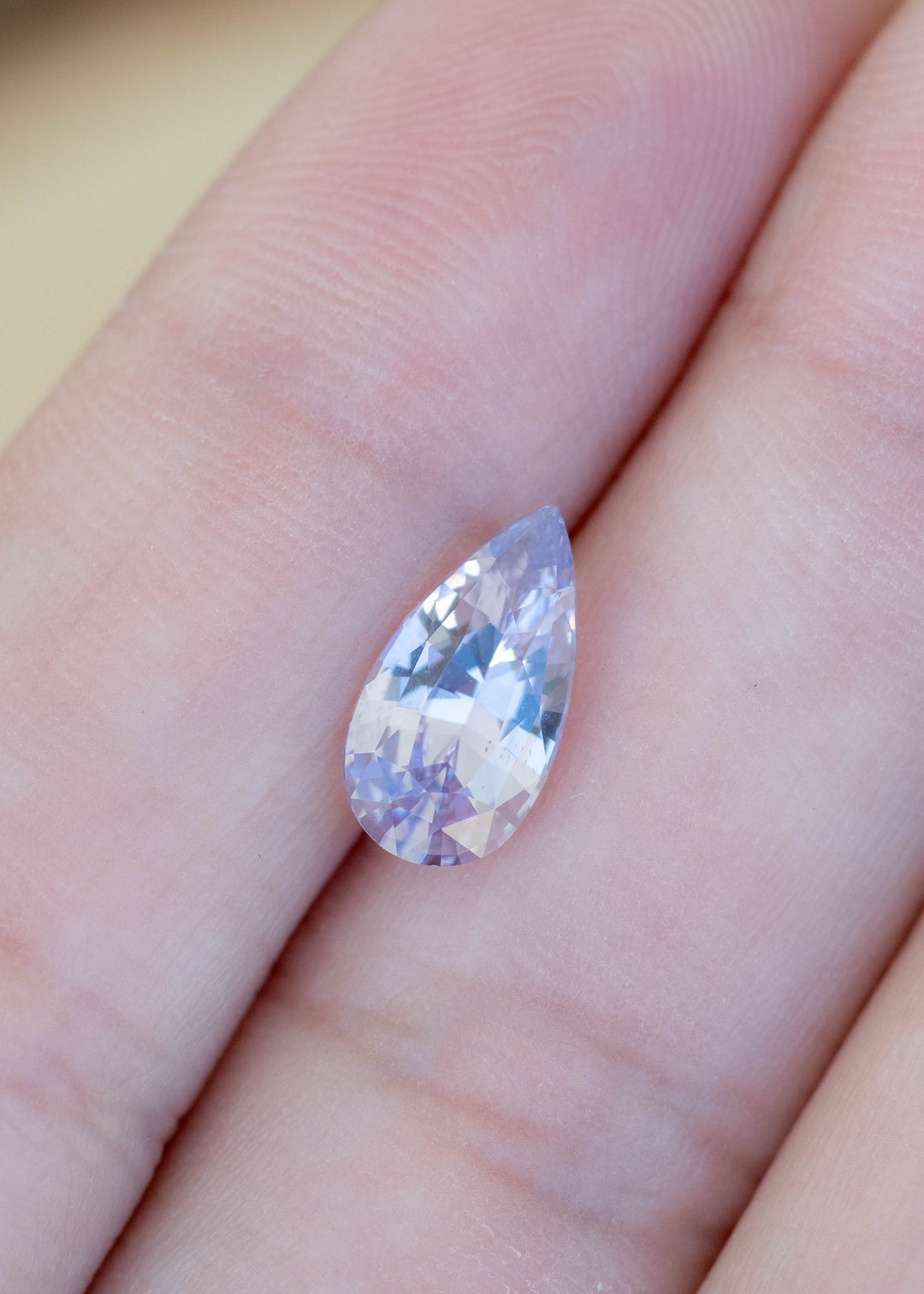 Loose 2.06 carat lavender pinkish purple sapphire shown on hand displaying a precision pear mixed cut from Madagascar.