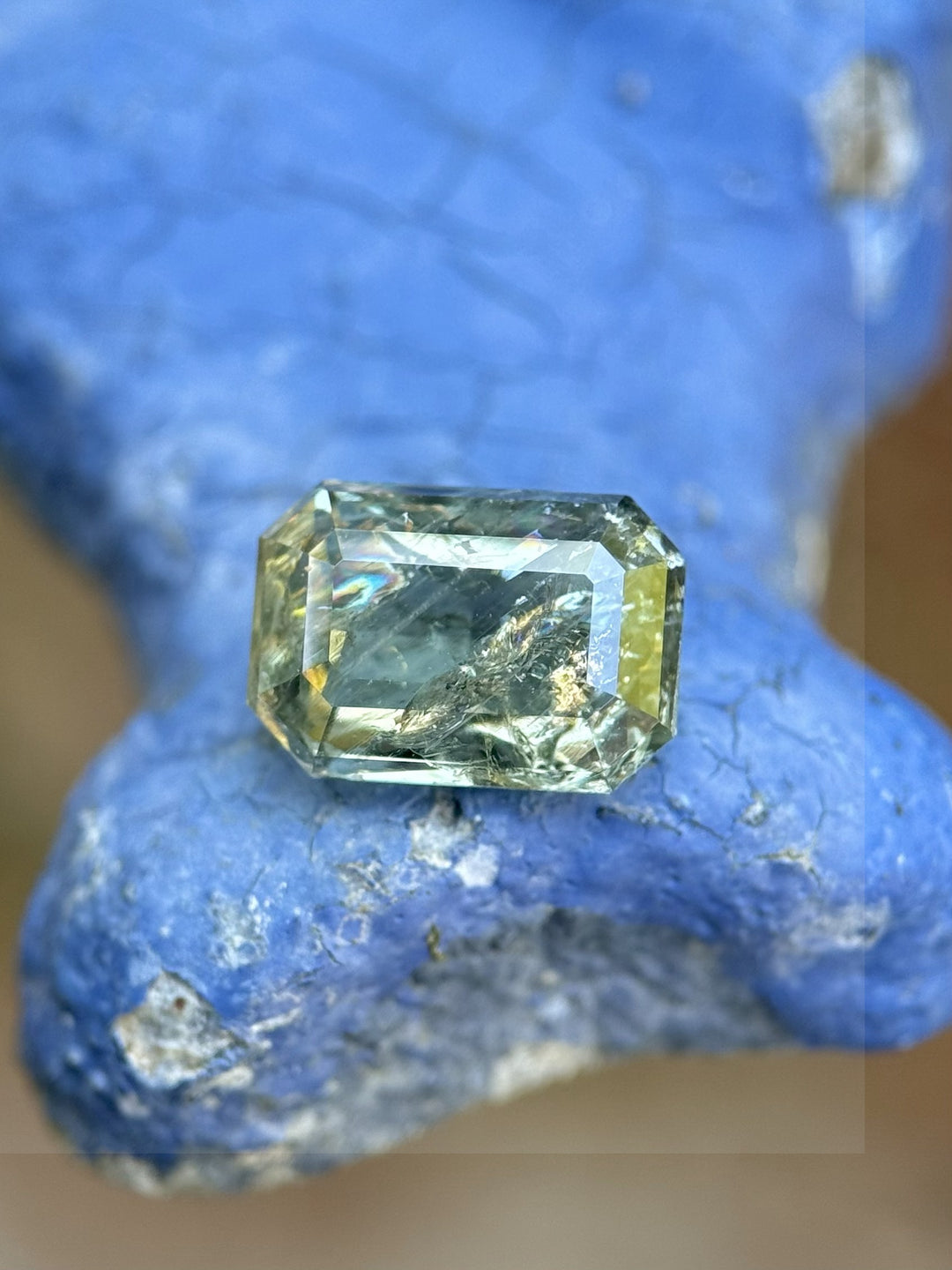 2.06-carat unheated sapphire with earthy teal and yellow hues on blue rock, modified emerald cut, Umba River Tanzania