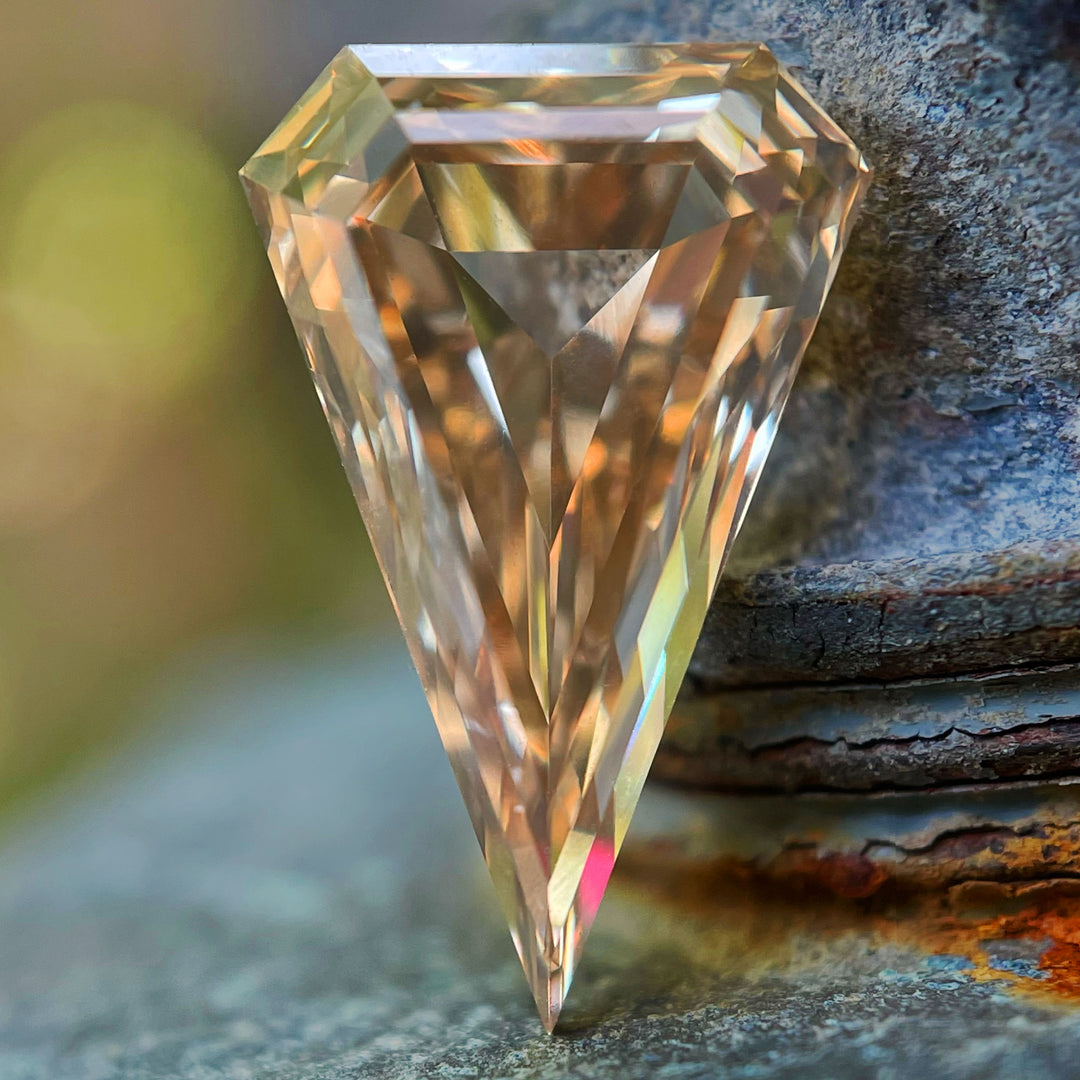 Close-up of a 2.10-carat elongated kite cut diamond with a rosy champagne hue, showcasing brilliant step-cut facets and superior VVS1 clarity.