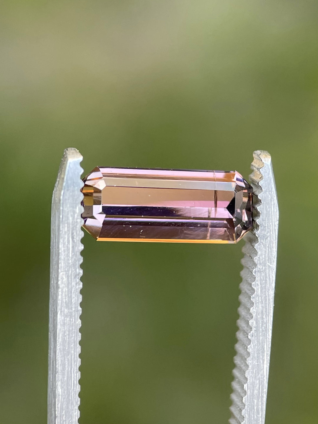 Side profile of a 2.12-carat Tanzanite with a custom elongated emerald cut, showcasing its pink and lavender hues in natural light.