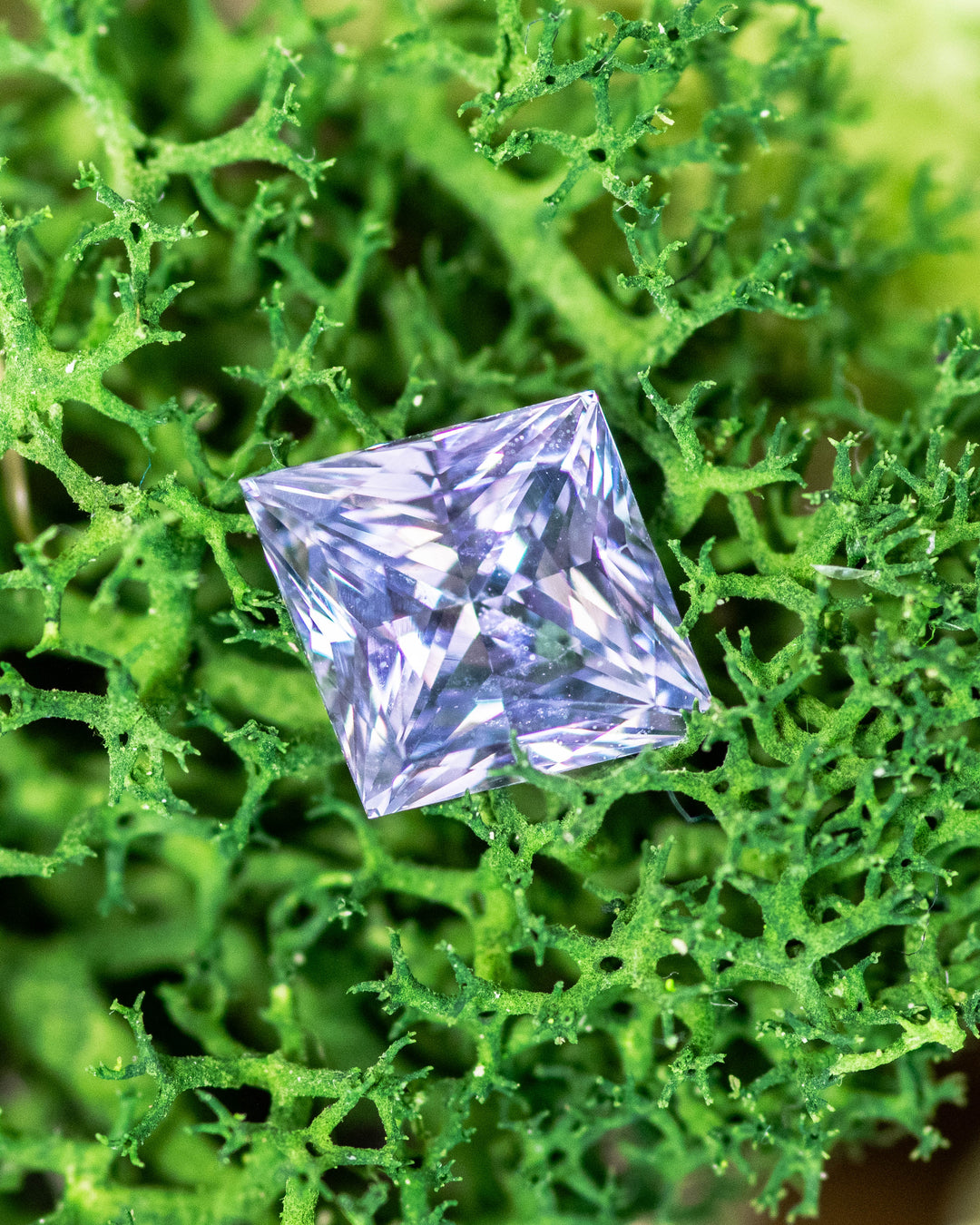 2.15 carat lilac gray lavender sapphire displayed on bright green moss, capturing natural light reflections through the custom kite cut facets, untreated gemstone from Sakaraha, Madagascar.
